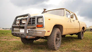 Aged yellow four wheel drive on property.