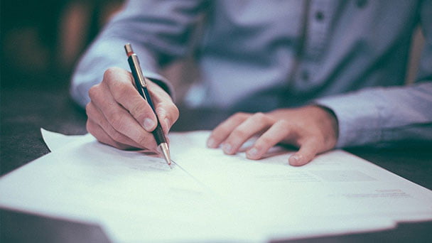 Man sitting at desk signing documents